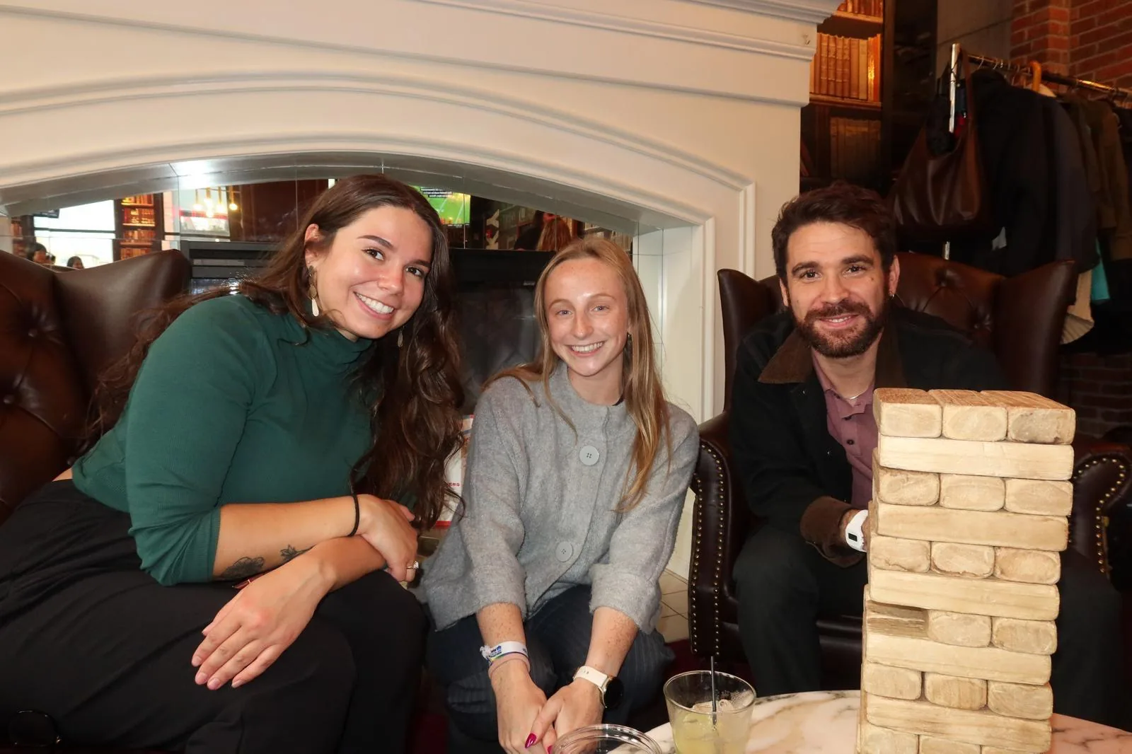 Three lab members smiling next to a giant Jenga tower