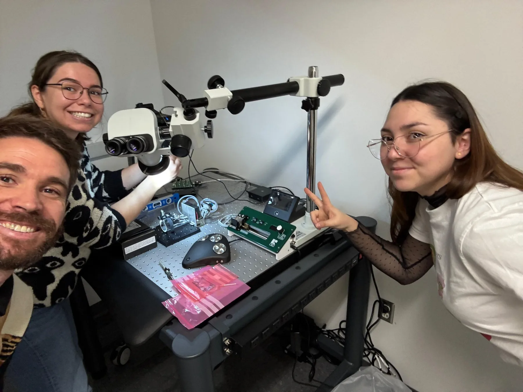 Two lab members smiling next to a stereotaxic surgery rig